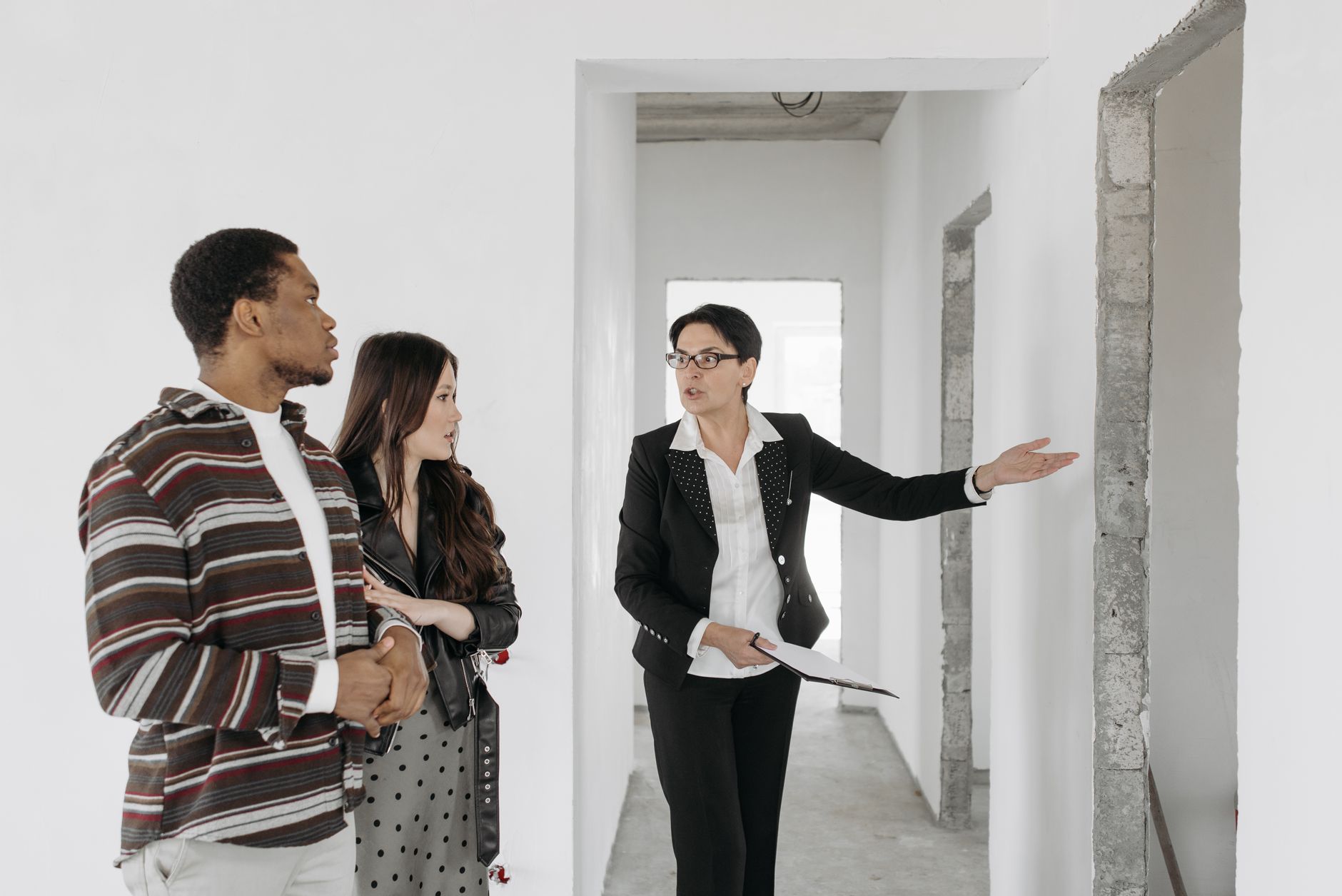 L'agent immobilier montre une maison à un couple, discutant des caractéristiques.