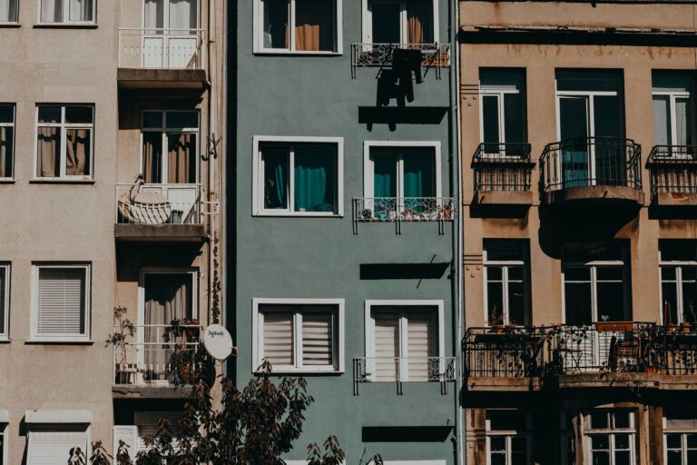 Façades d'immeubles résidentiels en ville, balcons, fenêtres, linge et plantes.