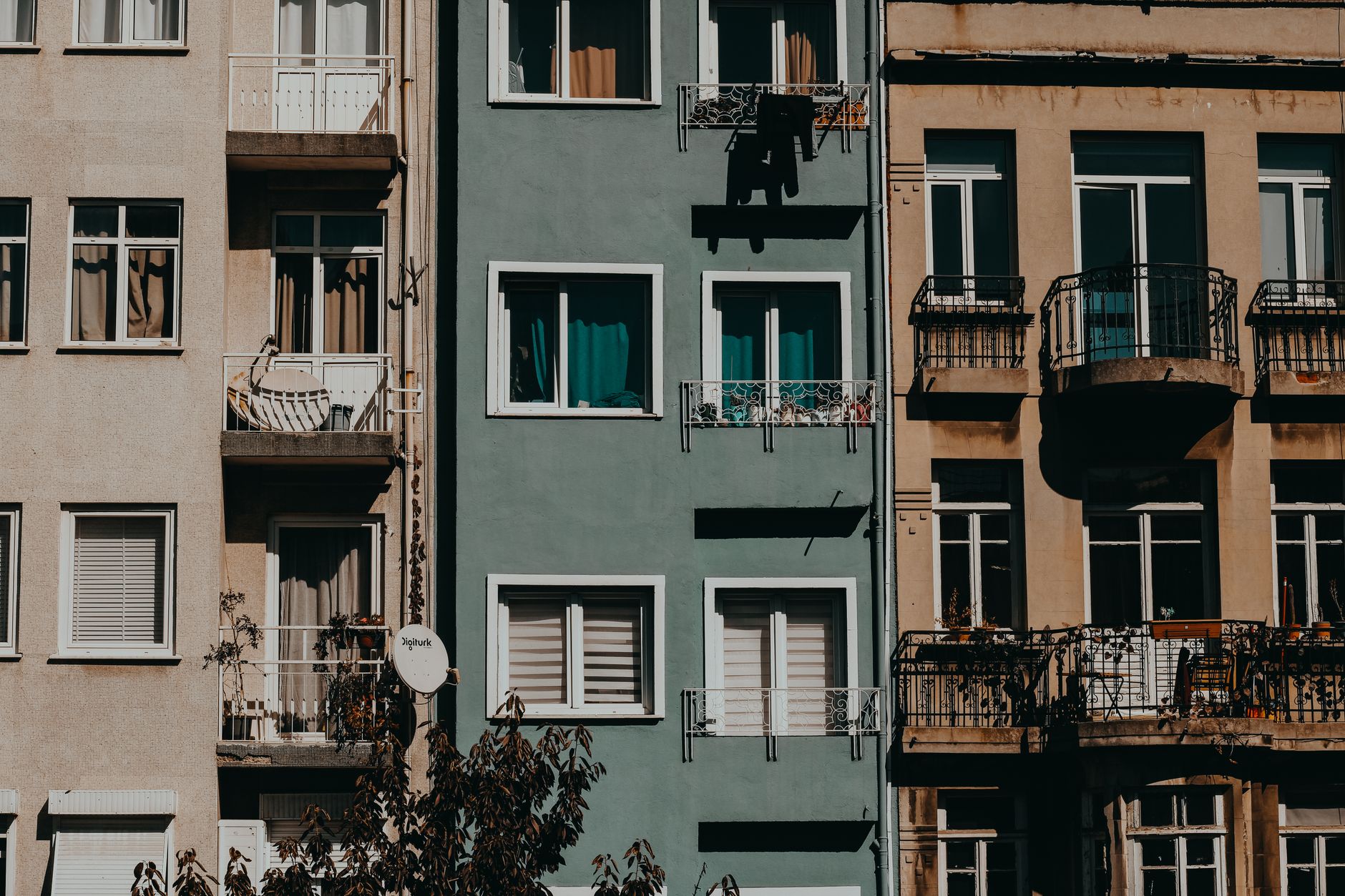 Façades d'immeubles résidentiels en ville, balcons, fenêtres, linge et plantes.