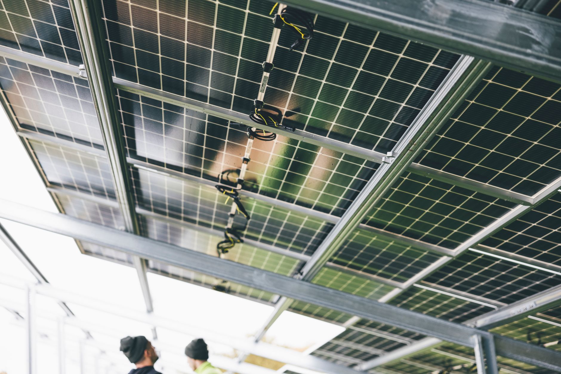 Installation de panneaux solaires sur une structure métallique, deux travailleurs en bas.