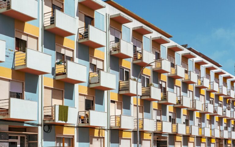 Façade d'immeuble résidentiel moderne avec balcons colorés sous ciel bleu.