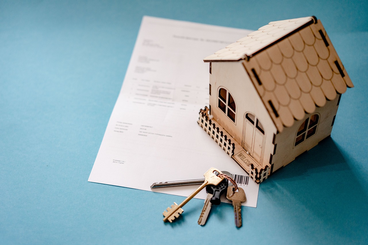 Petite maison en bois posée sur un document avec un trousseau de clés